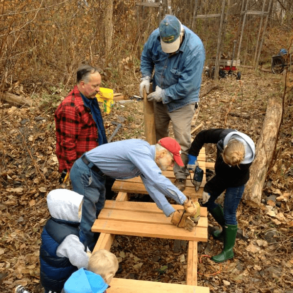Adults and children assemble a boardwalk on a forest trail in autumn